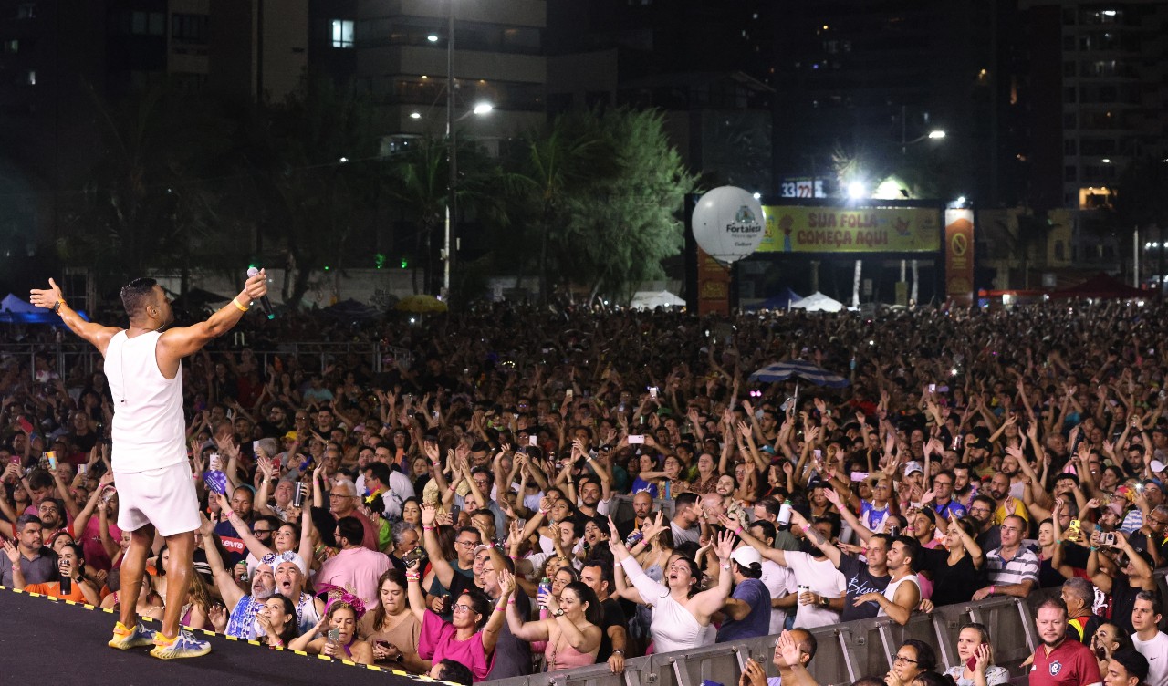 a foto mostra o público no aterrinho de frente para o palco durante o show do ara ketu